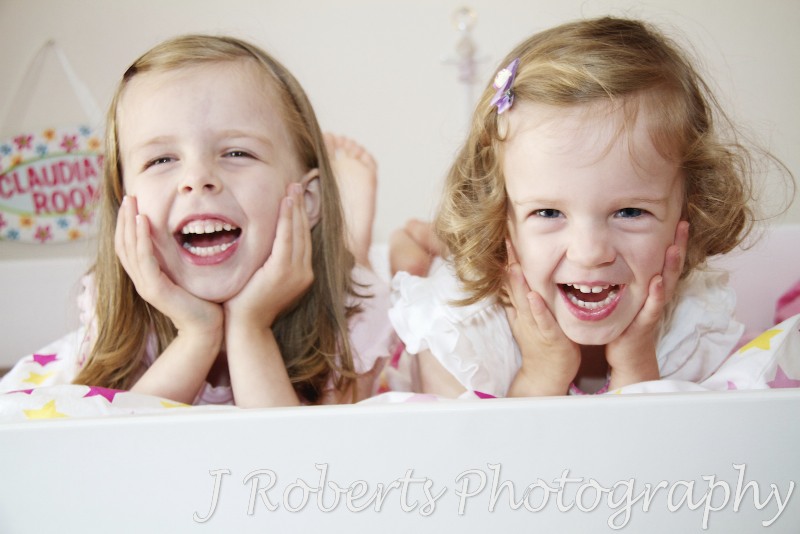 Sisters laughing together in their bedroom - family portrait photography sydney